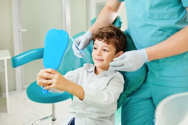 A young patient looking at their teeth with a mirror