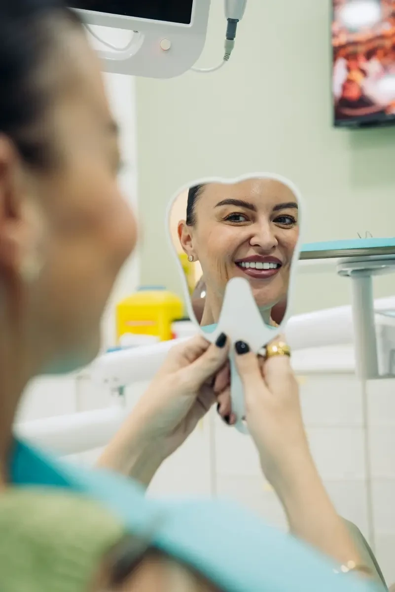 A patient checking her smile at Legacy Care